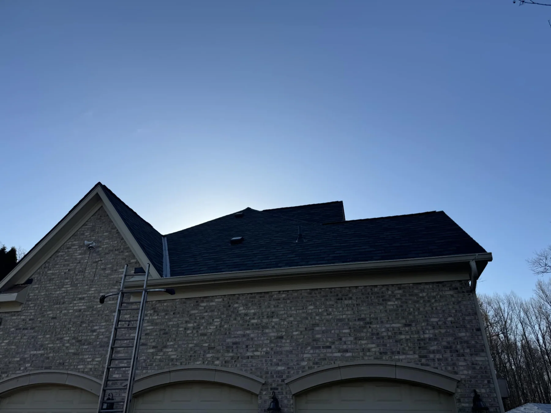 Dark architectural shingle roof on a stone residence